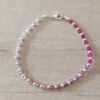 PULSERA DE TANZA CON MOSTACILLAS DEGRADE ROSA Y BOLITAS CON TERMINAL DE ACERO BLANCO. LARGO 18,5 CM