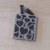 DIJE DE ACERO NEGRO COMBINADO CON ACERO COMUN SUPERPUESTO PARA PARTIR CON CORAZONES. TAMAÑO 25 X 30 MM