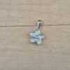 DIJE DE ACERO FLOR ESMALTADA EN CELESTE. TAMAÑO  9 MM